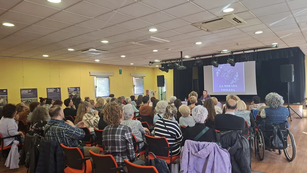 Público asistiendo a una charla con el logotipo de La Mirada Violeta proyectado en el escenario